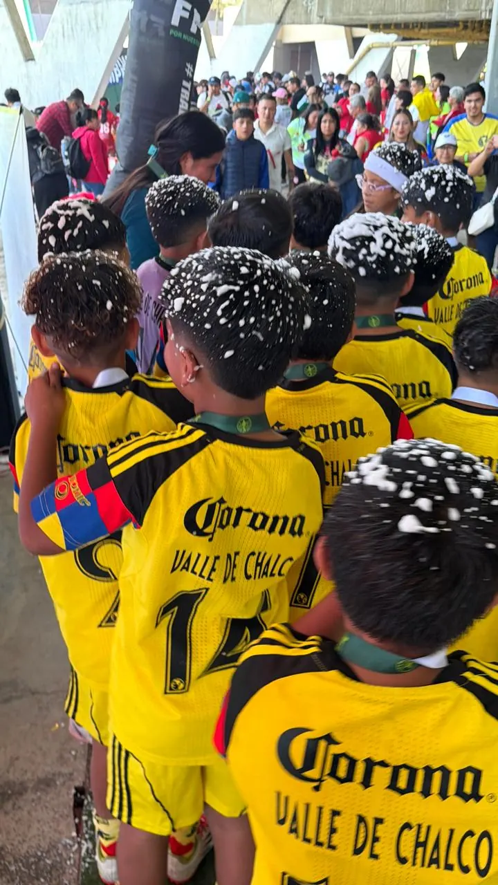 Niños campeones con uniforme amarillo de Valle de Chalco cubiertos de espuma después de ganar