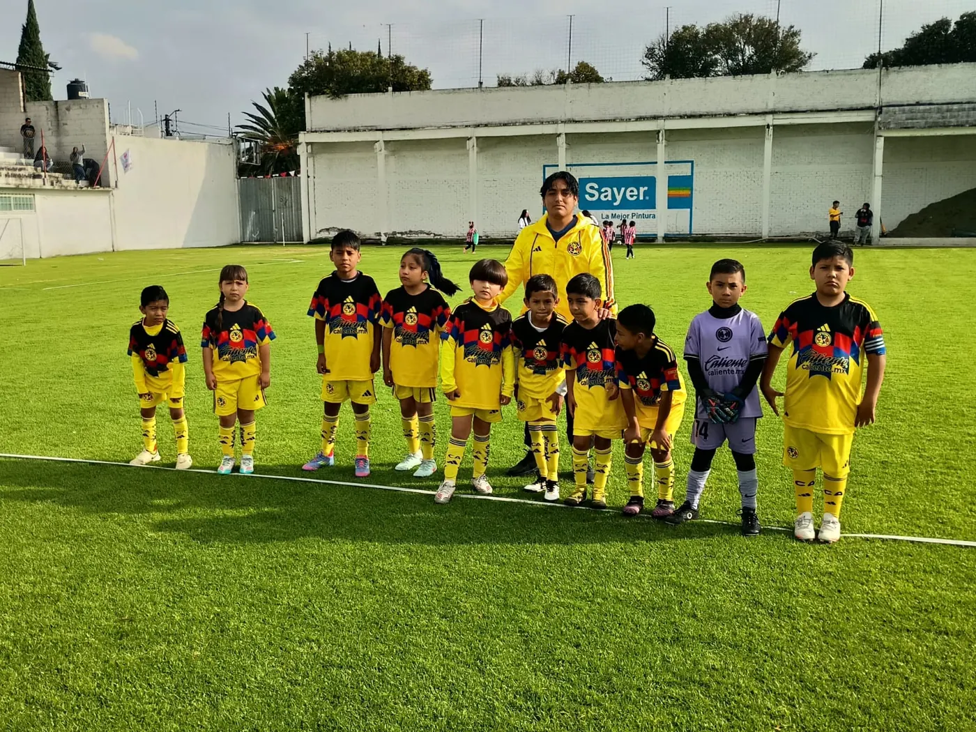 Equipo de la escuela de fútbol Nido Águila formado en la cancha junto a su entrenador