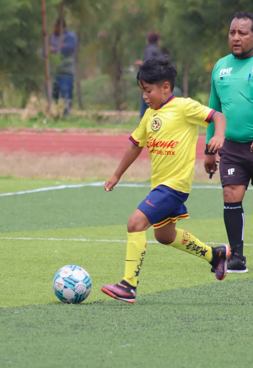 Jugador de Nido Águila a punto de patear el balón con el árbitro al fondo