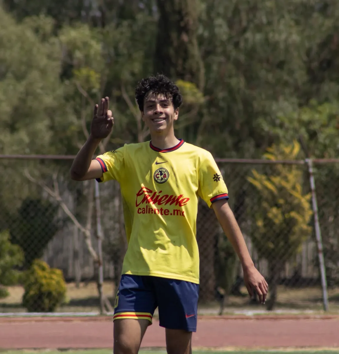 Jugador de Nido Águila sonriendo con camiseta amarilla y gesto de saludo en la cancha
